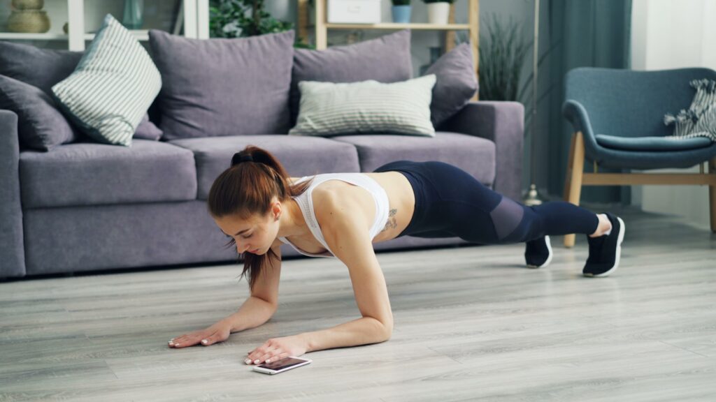 Vrouw die thuis push-ups doet op een yogamat - thuistraining voor beginners
