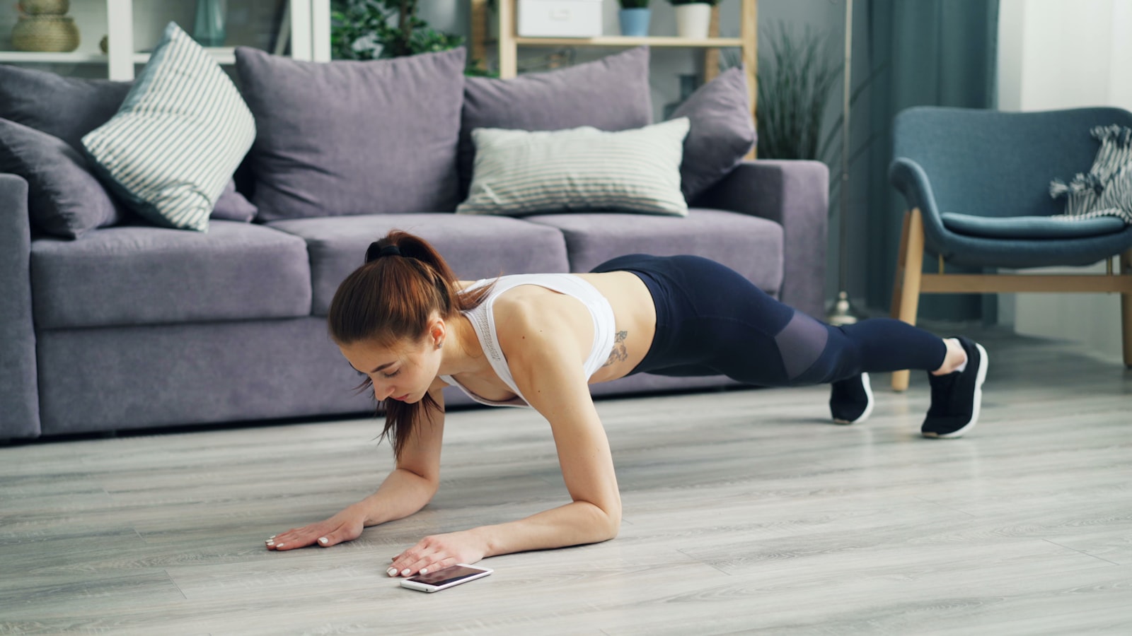 Vrouw die thuis push-ups doet op een yogamat - thuistraining voor beginners